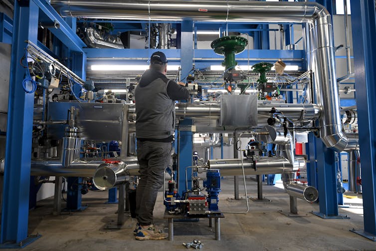 A person stands in front of a complicated piece of machinery.
