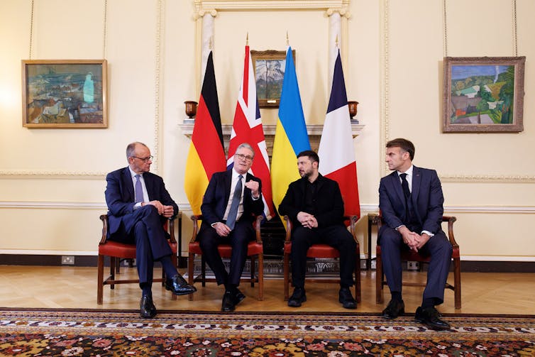 Friedrich Merz, Keir Starmer,  Volodymyr Zelenskyy and Emmanuel Macron sitting in front of their national flags.